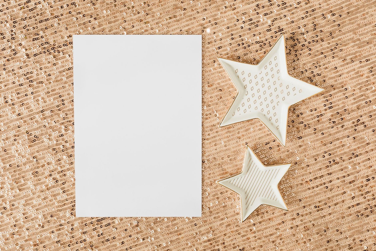 A blank paper on glittery sequins with decorative star shapes, ideal for festive designs.
