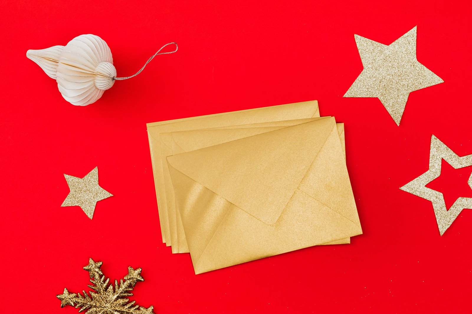 Golden envelopes and holiday decorations on a vibrant red background.